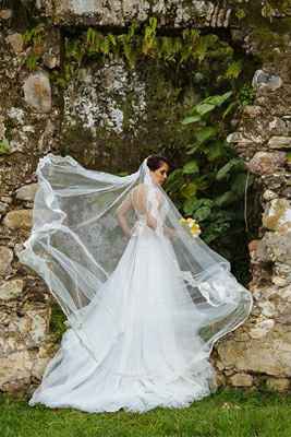 The bride picture in the garden near as wall, in the wedding dress