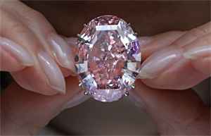 Pink color oval diamond in a ring the is held by hands
