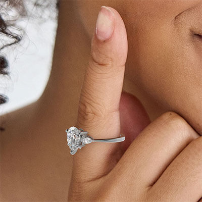 Anillo de compromiso de tres diamantes con diamantes en forma de pera laterales de 0,20 CTW